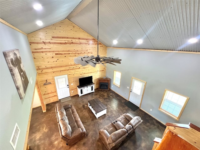 unfurnished living room with ceiling fan, wooden walls, and high vaulted ceiling