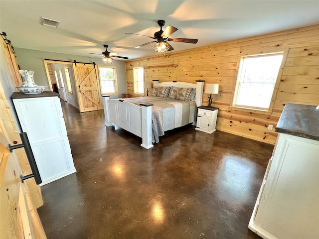 unfurnished bedroom featuring ceiling fan, wood walls, and a barn door