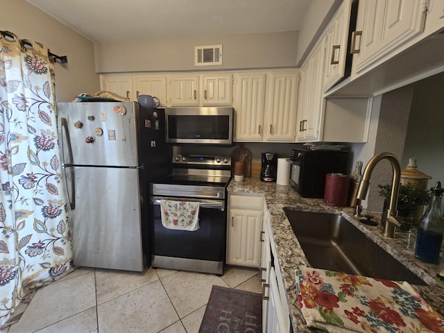 kitchen featuring light stone counters, light tile patterned floors, visible vents, appliances with stainless steel finishes, and a sink