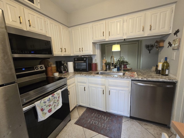 kitchen featuring visible vents, appliances with stainless steel finishes, white cabinetry, a sink, and light stone countertops