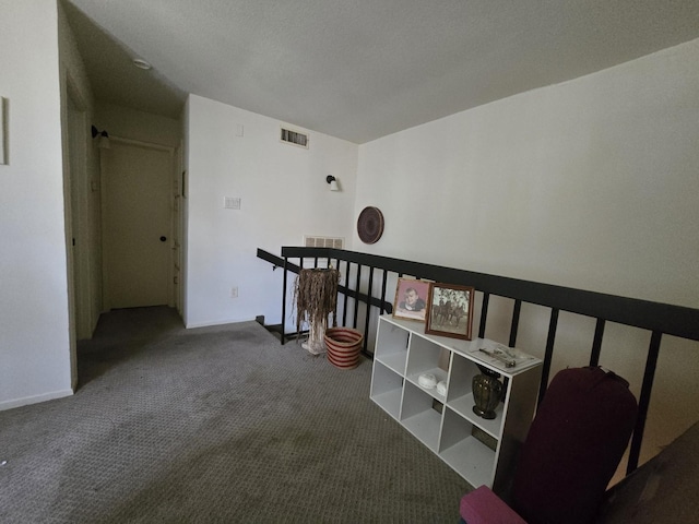 hallway featuring carpet floors, visible vents, and an upstairs landing