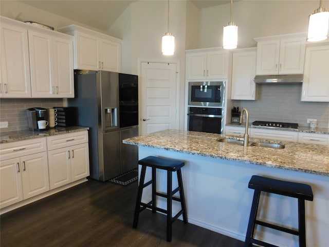 kitchen with white cabinets, backsplash, appliances with stainless steel finishes, and dark hardwood / wood-style floors