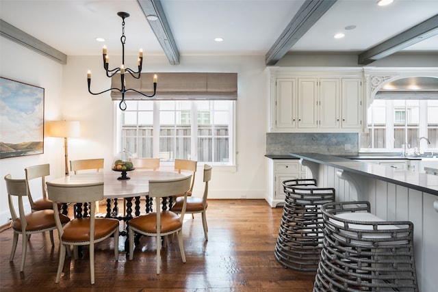 dining space with sink, beam ceiling, hardwood / wood-style floors, and an inviting chandelier