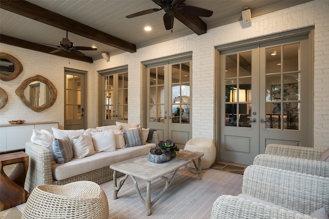 living room featuring beam ceiling, ceiling fan, brick wall, and french doors