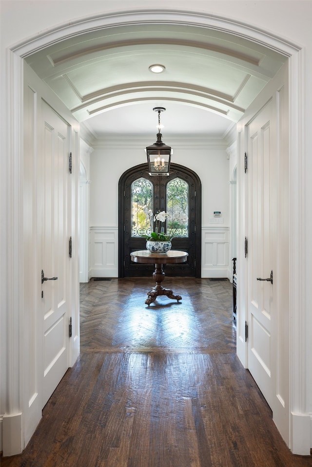 entrance foyer featuring a notable chandelier, crown molding, and dark hardwood / wood-style floors