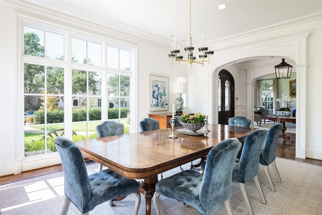 dining room with ornamental molding, an inviting chandelier, and light wood-type flooring