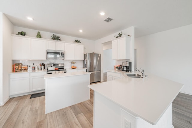 kitchen with a sink, stainless steel appliances, visible vents, a peninsula, and light countertops