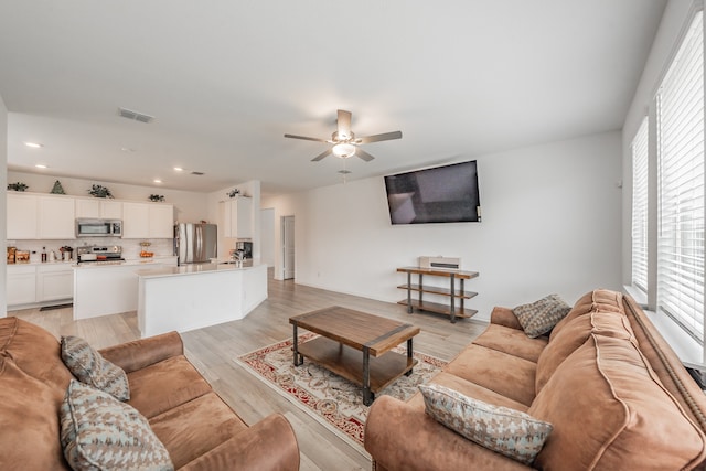 living room featuring plenty of natural light, ceiling fan, and light hardwood / wood-style floors