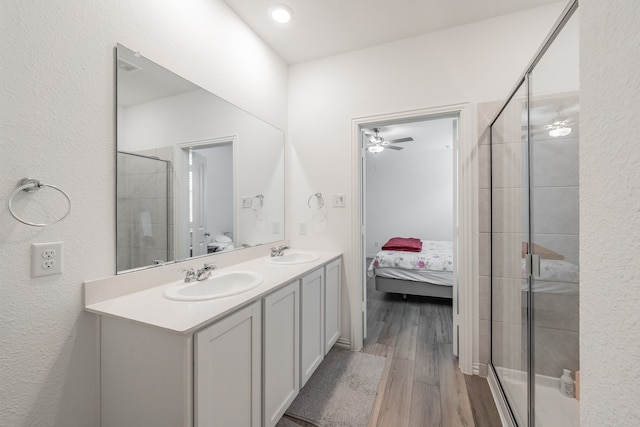 bathroom featuring a shower with shower door, ceiling fan, double sink vanity, and hardwood / wood-style flooring