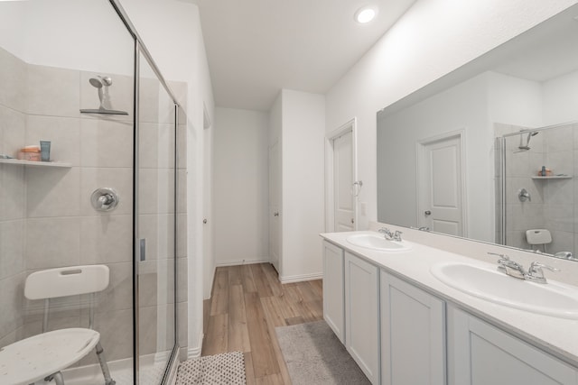 bathroom featuring a shower with door, hardwood / wood-style floors, and dual bowl vanity