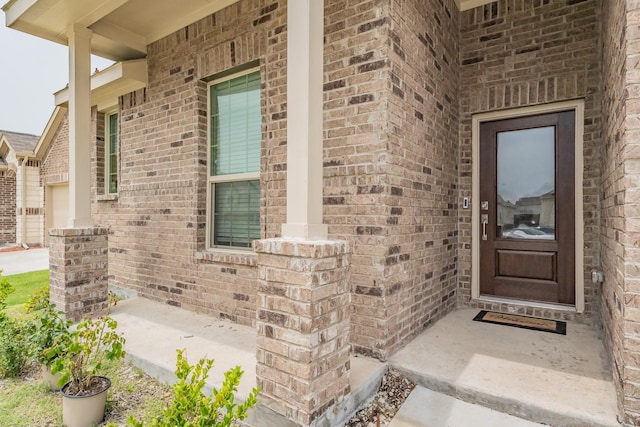 doorway to property with covered porch and brick siding