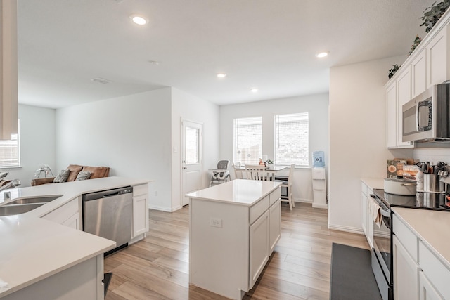 kitchen featuring recessed lighting, a sink, light wood-style floors, a kitchen island, and appliances with stainless steel finishes