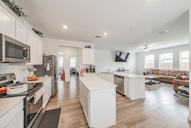 kitchen featuring a center island, visible vents, light wood-style flooring, light countertops, and appliances with stainless steel finishes