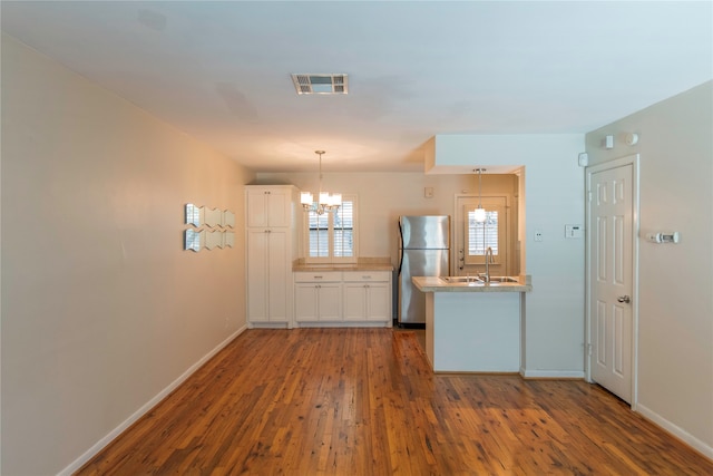 kitchen featuring stainless steel fridge, white cabinetry, hardwood / wood-style floors, and sink