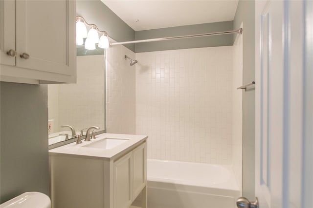 full bathroom featuring tiled shower / bath, vanity, and toilet