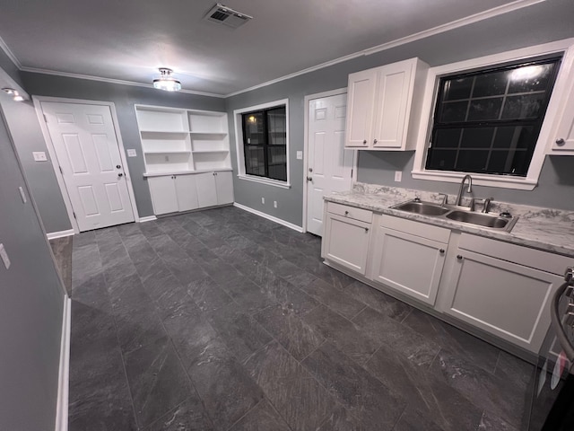 kitchen with dark tile patterned floors, sink, crown molding, white cabinets, and stove