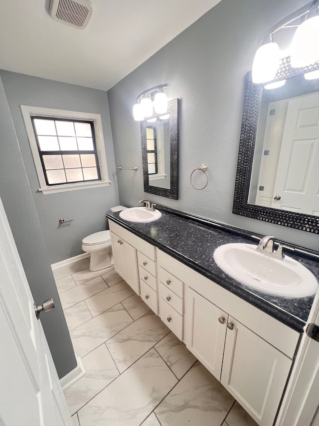 bathroom featuring toilet, dual bowl vanity, and tile patterned floors