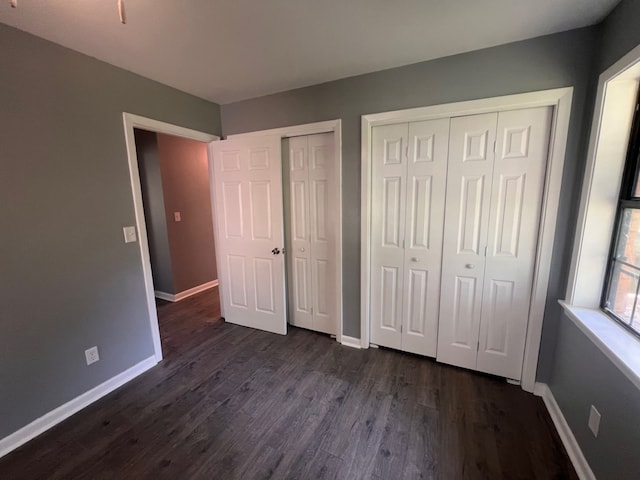 unfurnished bedroom with dark hardwood / wood-style flooring and two closets