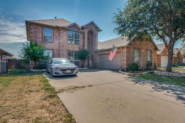 view of front of house featuring a front lawn, central AC unit, and a garage