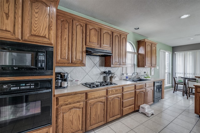 kitchen featuring decorative backsplash, sink, black appliances, a textured ceiling, and light tile patterned flooring