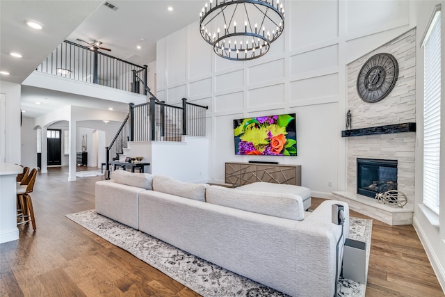 living room featuring a fireplace, hardwood / wood-style flooring, a high ceiling, and ceiling fan