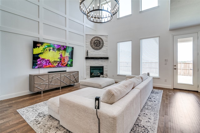 living room with a towering ceiling, dark wood-type flooring, a healthy amount of sunlight, and an inviting chandelier