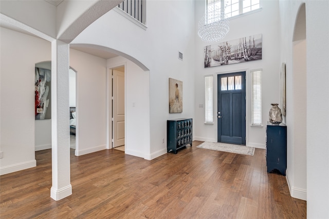 entryway featuring a wealth of natural light, wood-type flooring, a high ceiling, and a notable chandelier