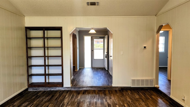 entrance foyer featuring vaulted ceiling, a textured ceiling, wood walls, and dark wood-type flooring