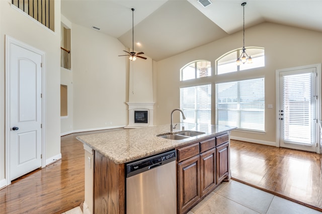 kitchen with ceiling fan with notable chandelier, stainless steel dishwasher, light hardwood / wood-style floors, and an island with sink