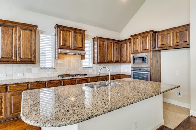 kitchen featuring appliances with stainless steel finishes, sink, tasteful backsplash, and light stone counters