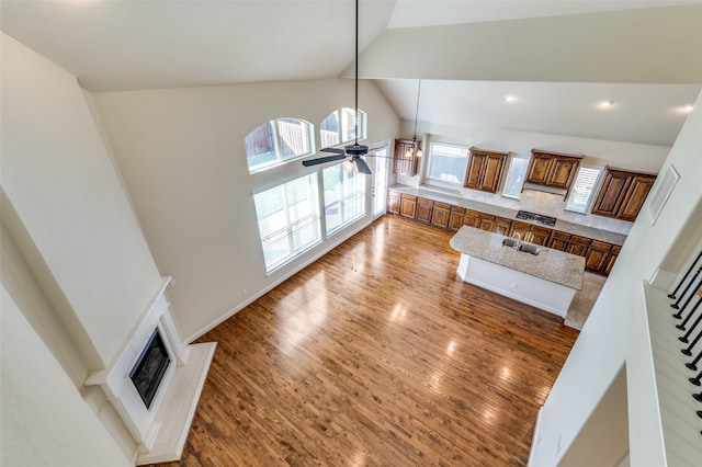 living room featuring ceiling fan, hardwood / wood-style floors, sink, and high vaulted ceiling