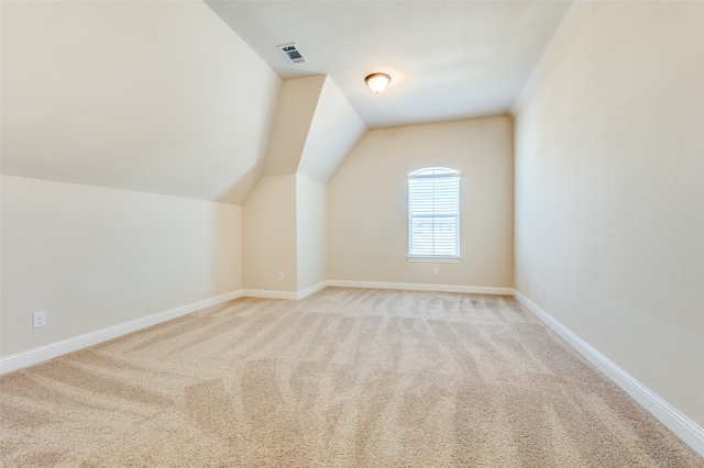 additional living space featuring vaulted ceiling and light carpet