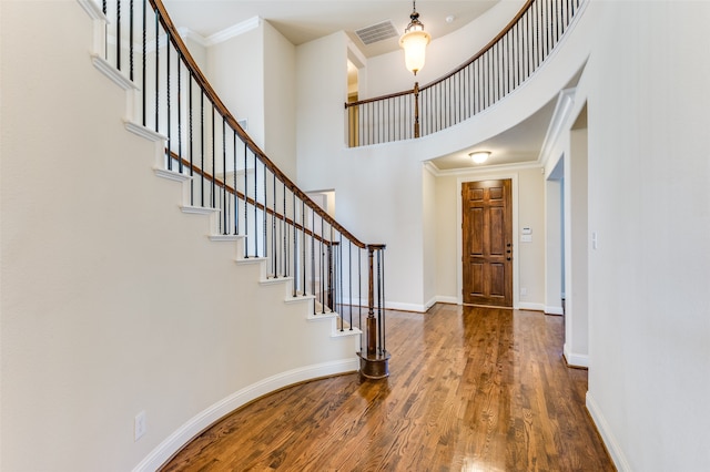 entryway featuring a high ceiling, hardwood / wood-style floors, and ornamental molding