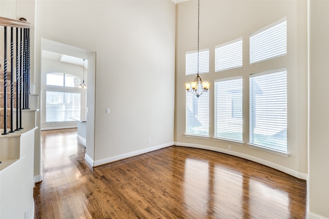 interior space with hardwood / wood-style flooring, a high ceiling, plenty of natural light, and an inviting chandelier