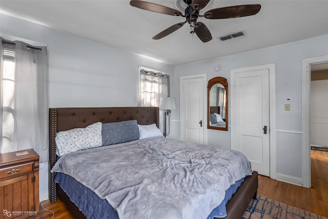 bedroom featuring ceiling fan, dark wood-type flooring, and two closets