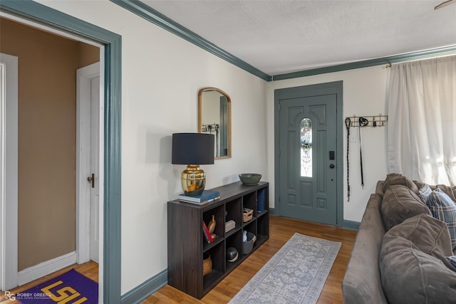 foyer entrance with hardwood / wood-style floors, crown molding, and a textured ceiling