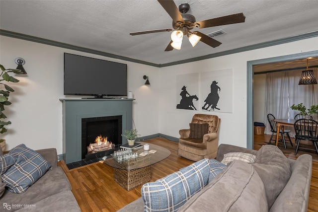 living room featuring a textured ceiling, ornamental molding, hardwood / wood-style flooring, and ceiling fan