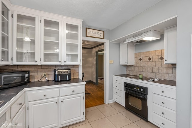 kitchen featuring white cabinetry, black appliances, light tile patterned flooring, backsplash, and custom exhaust hood