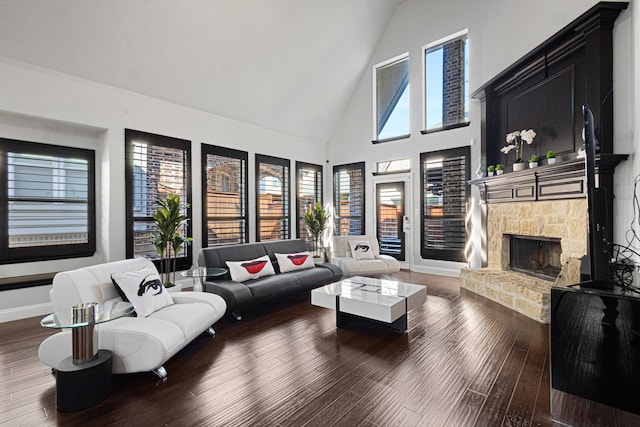 living room featuring high vaulted ceiling, a stone fireplace, and hardwood / wood-style flooring