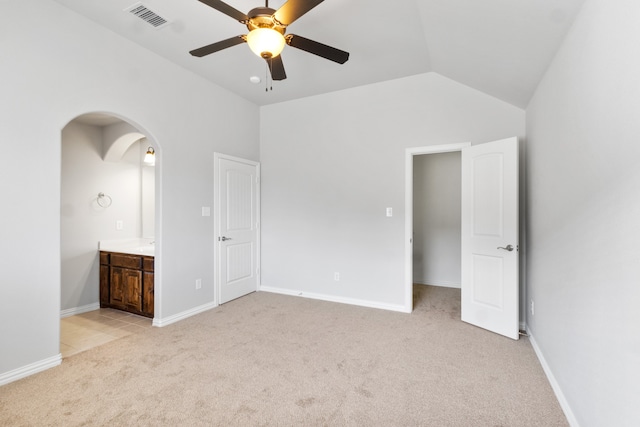 unfurnished bedroom featuring ceiling fan, lofted ceiling, light colored carpet, and ensuite bathroom