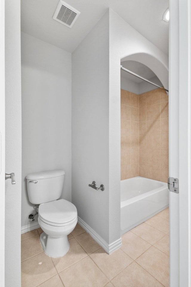 bathroom with toilet, tiled shower / bath combo, and tile patterned floors