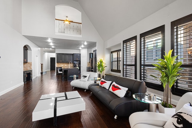 living room featuring high vaulted ceiling, dark wood-type flooring, and sink