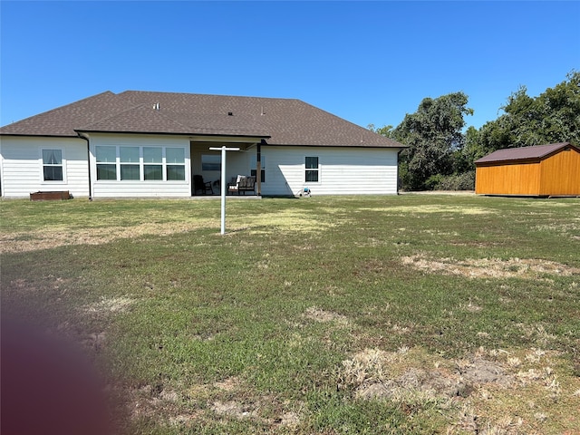 rear view of property with a yard and a storage shed