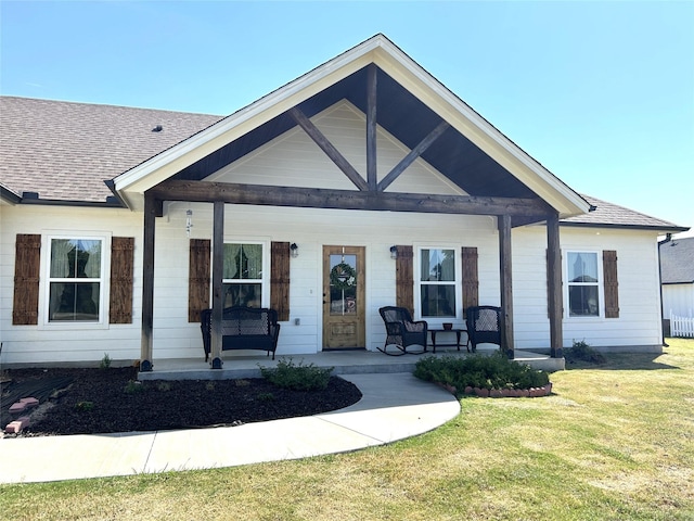 view of front of property featuring a porch, roof with shingles, and a front yard