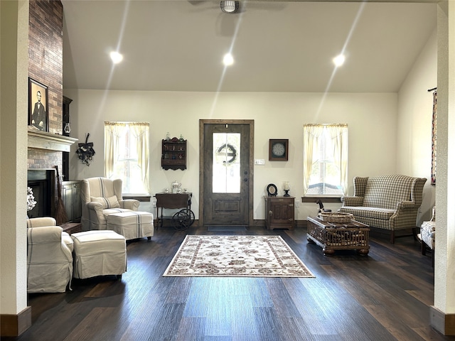 living room with ceiling fan, vaulted ceiling, dark hardwood / wood-style flooring, and a fireplace