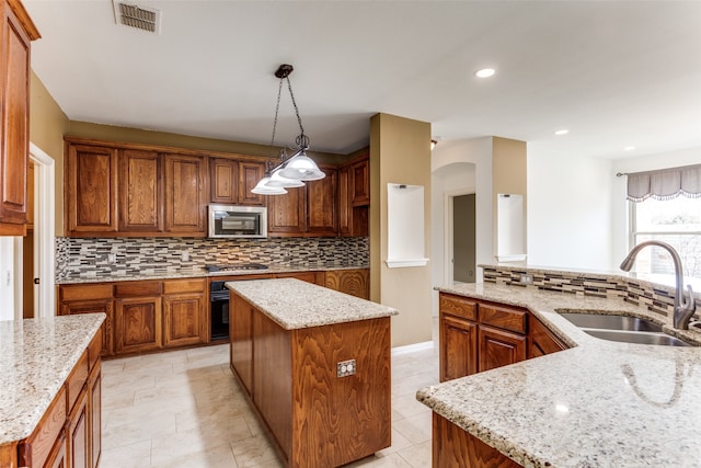 kitchen featuring hanging light fixtures, a center island, stainless steel appliances, and light stone countertops