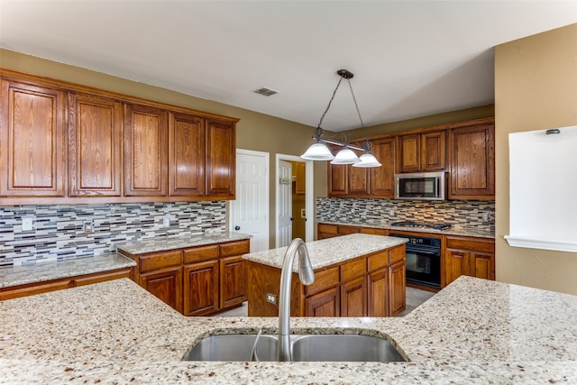 kitchen featuring light stone counters, tasteful backsplash, pendant lighting, stainless steel appliances, and sink