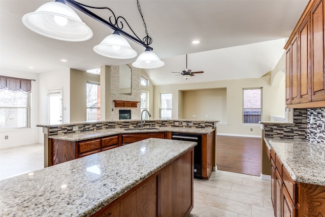 kitchen with hanging light fixtures, lofted ceiling, sink, and light stone counters