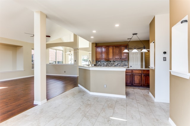 kitchen with light hardwood / wood-style floors, tasteful backsplash, decorative light fixtures, ceiling fan, and ornate columns