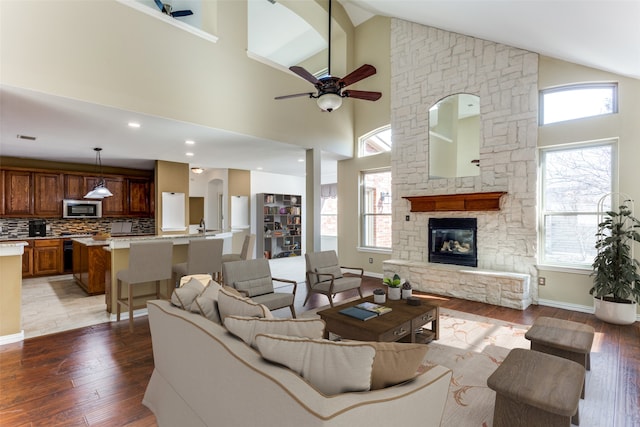 living room with ceiling fan, light hardwood / wood-style flooring, and high vaulted ceiling